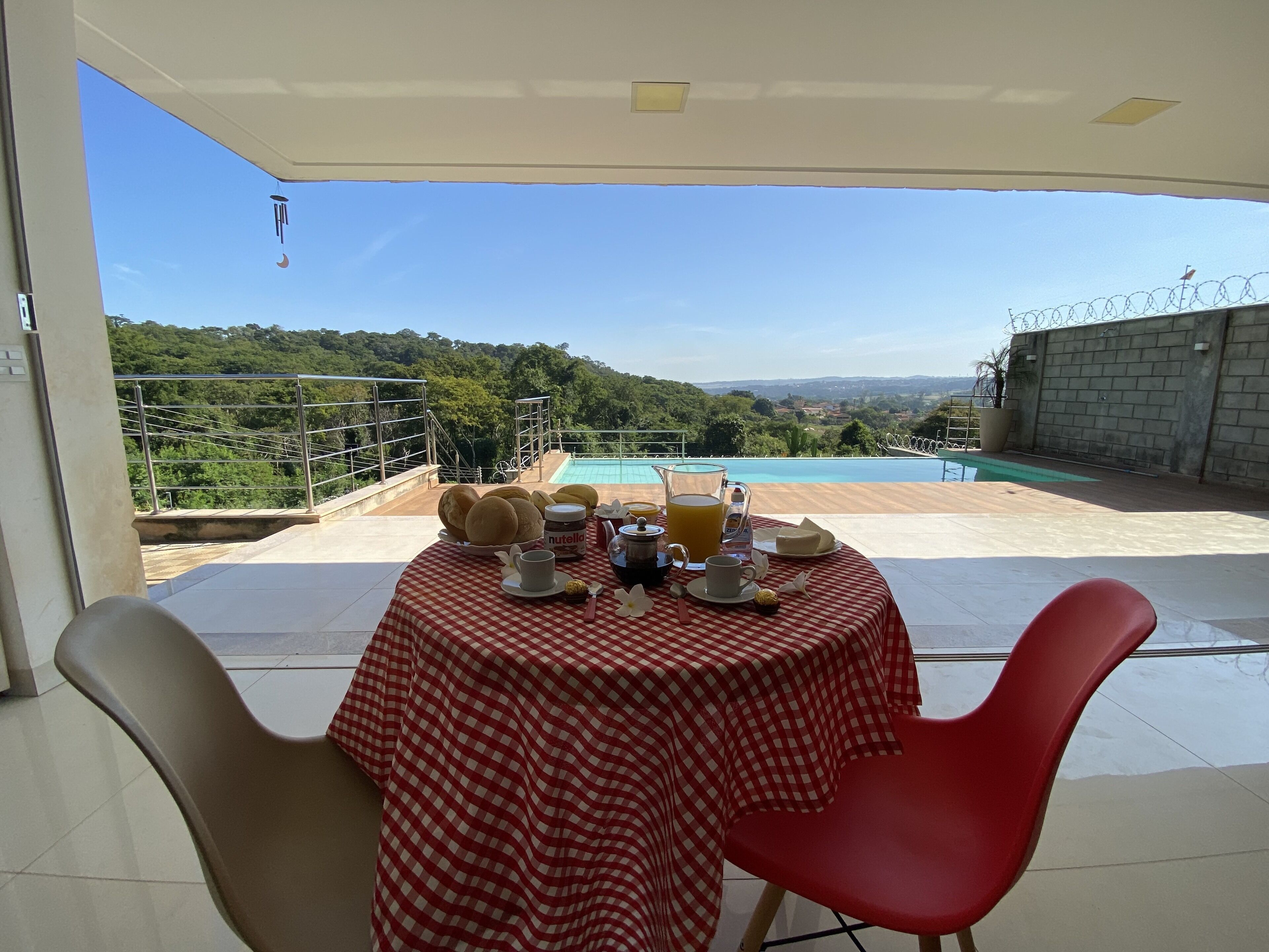 A dining table with a red and white checkered tablecloth, a pitcher of orange juice, a cup, and a plate of food.