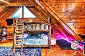 Une chambre mansardée chaleureuse, avec un lit superposé en bois, un petit bureau et une fenêtre.