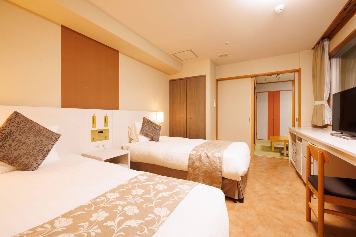 Habitació d'hotel amb dos llits, escriptori, televisió i armari.