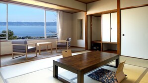 Une pièce de style japonais traditionnel, avec un sol recouvert de tatamis, une table en bois et une vue sur la mer.