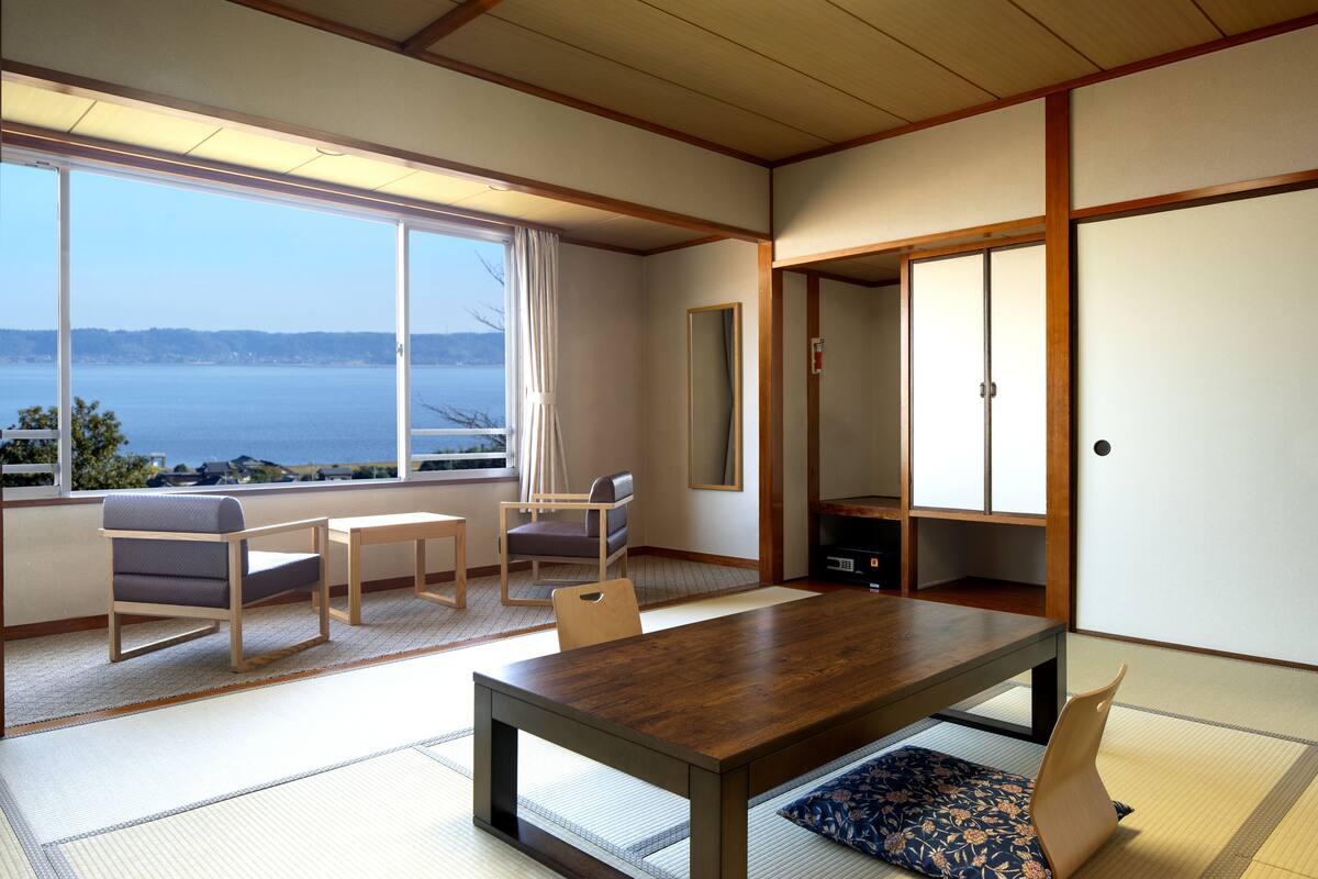 Habitació tradicional japonesa amb fusta de tatami, una taula de fusta i vista al mar.
