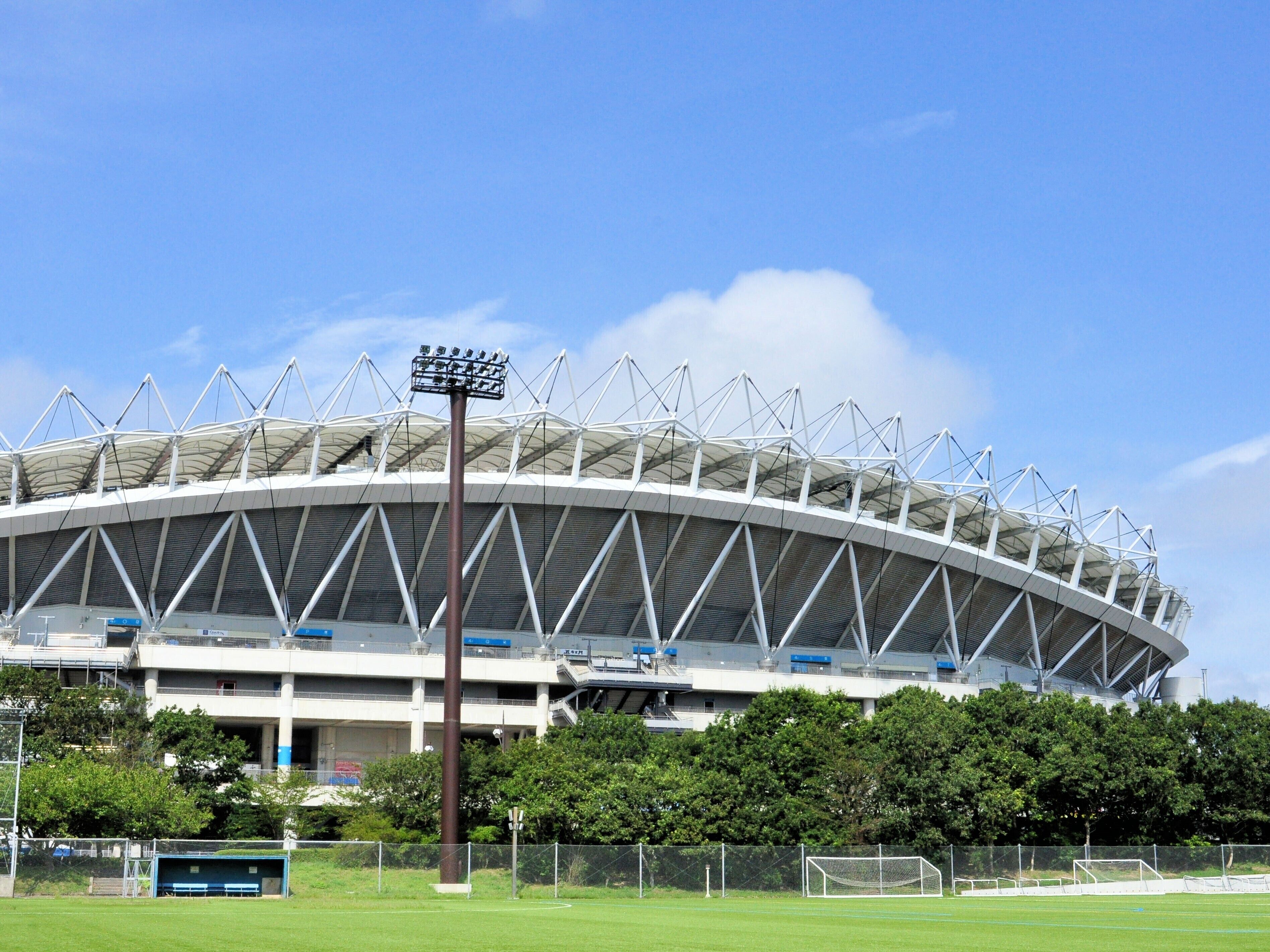 Um estádio grande com uma estrutura de cobertura marcante e áreas de assentos.