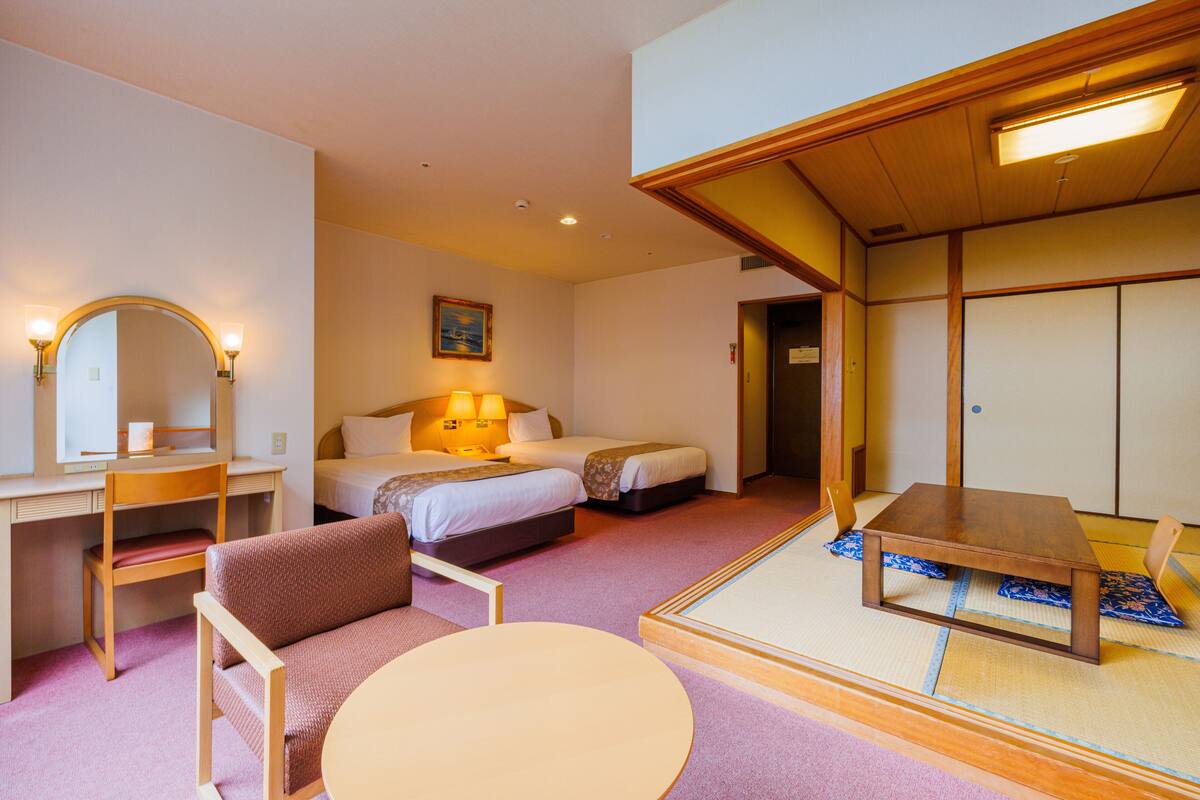 Una habitació d'hotel amb llit, taula de nit, cadira i una taula rodona petita.