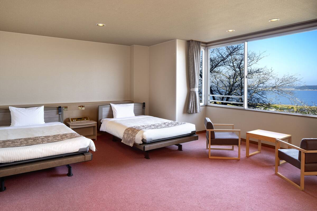 Habitació d'hotel amb dos llits, una taula i una cadira.