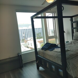 Quarto com cama de dossel, uma janela grande e vista para edifícios.