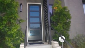A modern building entrance with a glass door, a metal staircase, and a sign indicating a control system. - Discount for a 30 day stay! Luxury 4 all queen beds. Walk to the harbor + views (San Pedro)
