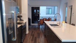 A modern kitchen with stainless steel appliances, a large island with a sink, and wooden flooring. - Discount for a 30 day stay! Luxury 4 all queen beds. Walk to the harbor + views (San Pedro)