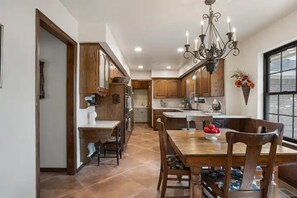 A spacious kitchen with wooden cabinets, a dining table with chairs, and a chandelier.