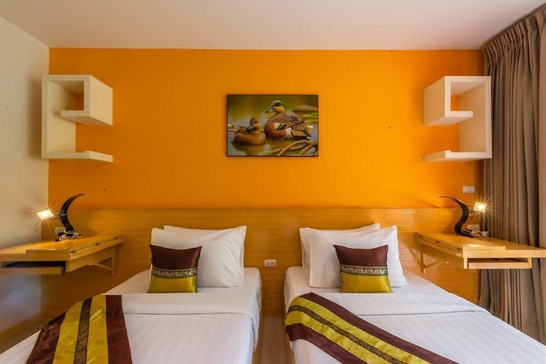 A hotel room with two beds, a painting of ducks on the wall, and built-in shelves.
