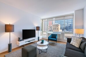 A modern living room with a flat-screen TV, a sofa, a coffee table, and a chair.