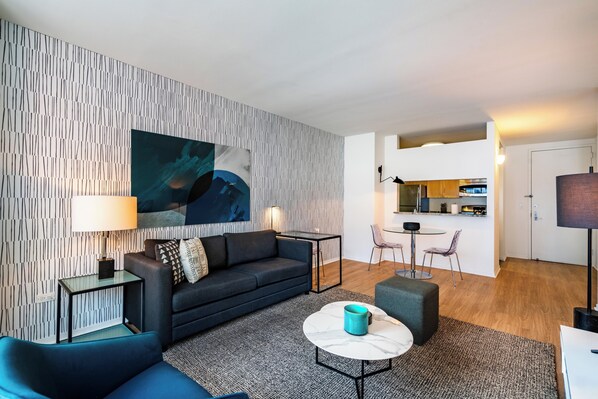 A modern living room with a sofa, a coffee table, and a painting on the wall.