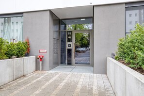 Enter through the door marked 18, flanked by lush greenery and a water supply point nearby.