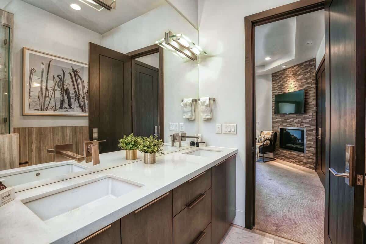 Un baño moderno con un espejo grande, lavamanos dobles y una planta en maceta.