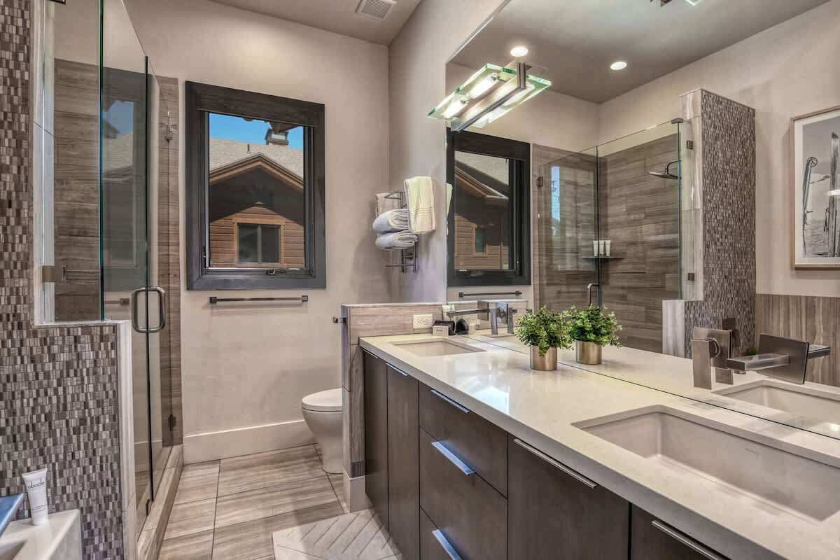 A modern bathroom with a large mirror, a glass shower enclosure, and a built-in sink.