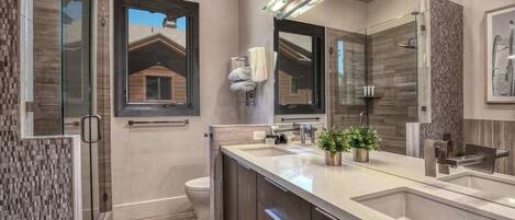 A modern bathroom with a large mirror, a glass shower enclosure, and a built-in sink.