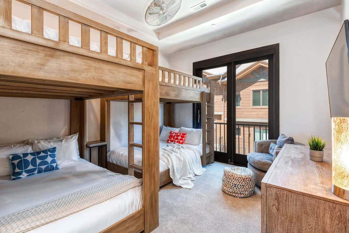 Ein Zimmer mit Etagenbetten, einer Schlafcouch, einem kleinen Tisch und einer Zimmerpflanze.