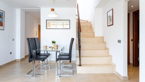 Un intérieur moderne avec un escalier, un coin repas avec des chaises et une table agrémentée d’objets décoratifs.