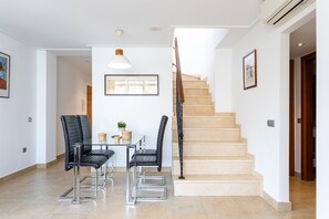 A modern interior with a staircase, a dining area with chairs, and a table with decorative items.