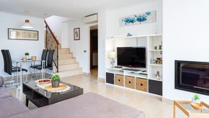 Un salon moderne avec un canapé, une table basse, un téléviseur et un escalier.