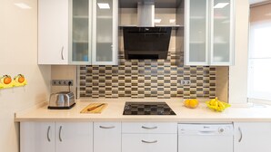 Une cuisine moderne avec des meubles blancs, une cuisinière noire et un dosseret carrelé.