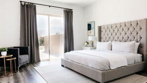 Une chambre avec un grand lit, une chaise, une petite table avec une plante et une vue sur l’extérieur.