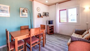 Ein kompakter Wohnraum mit Esstisch, Stühlen, Fernseher und einer Couch.