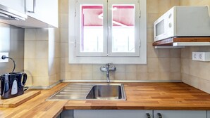 Eine moderne Küche mit einer Holzausziehtafel, einer Edelstahlspüle und einem Fenster mit rosafarbenen Vorhängen.