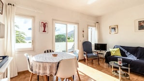 Een woonkamer met een ronde eettafel, stoelen, een bank en een televisie.