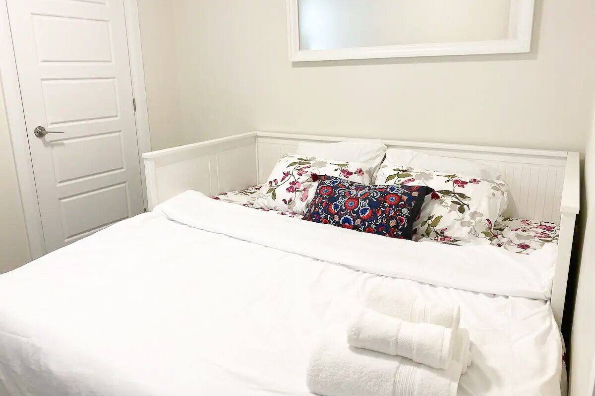 A neatly made bed with floral-patterned pillows and a white comforter.