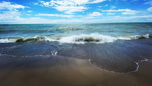 A beach with waves reaching the shore under a partly cloudy sky. - Brand New Basement Apt next to Beach & Go Train (Pickering)