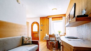 Una habitación acogedora con sofá, una mesa de comedor de madera y una zona de cocina.
