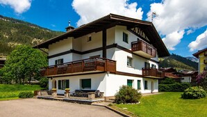 Un edificio de dos pisos con balcones, un patio cubierto y montañas al fondo.