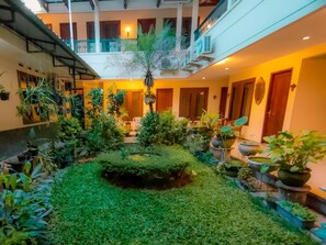 A courtyard with a central circular garden, surrounded by potted plants and a variety of greenery. - Mandala Wisata Hotel (Surakarta)