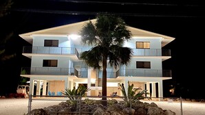 A two-story building with balconies, a palm tree in front, and a paved area in front. - Re-energize at our spacious condo! Enjoy 10% off stays of 7+ days. Book now! (Key Largo)