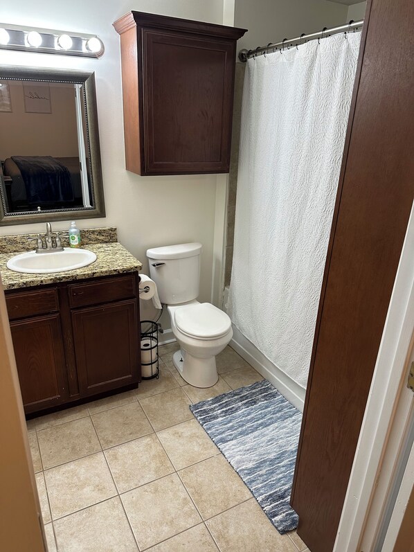 A bathroom with a vanity, sink, mirror, and toilet.