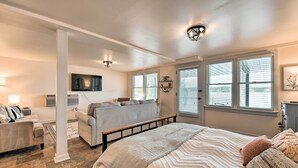 A bedroom with a large bed, a sofa, a TV, and a window with blinds. - Dreamy Lake Norman Cottage w/ Panoramic Lake Views (Troutman)