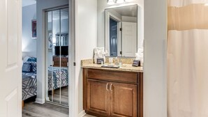 Une salle de bain avec un meuble-lavabo en bois, un miroir et un rideau de douche.