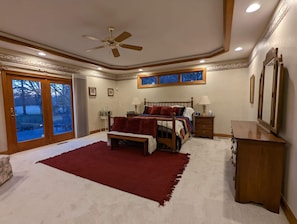 A bedroom with a large bed, a ceiling fan, a nightstand, a dresser, and a window with a view of trees. - The Country View Estate in Beavercreek OH. Close to many beautiful hiking trails (Bellbrook)