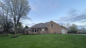 A single-story brick house with a sloped roof, a garage, and a well-maintained lawn.
