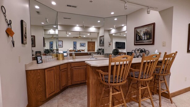 A kitchen with a large island, wooden chairs, and a dining table.