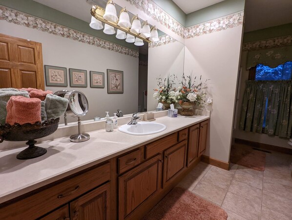 Un baño con un tocador de madera, un espejo grande, un lavamanos y una lámpara decorativa.