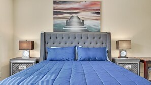 Um quarto com uma cama grande, duas mesas de cabeceira e um quadro na parede.