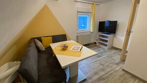 Un espacio habitable compacto con sofá, una mesita, televisor y ventana.