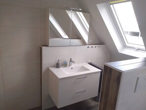 A modern bathroom with a skylight, a white sink, and a mirror above it. - Apartment on Lake 'Altmühlsee' with Terrace & Wi-Fi (Gunzenhausen)
