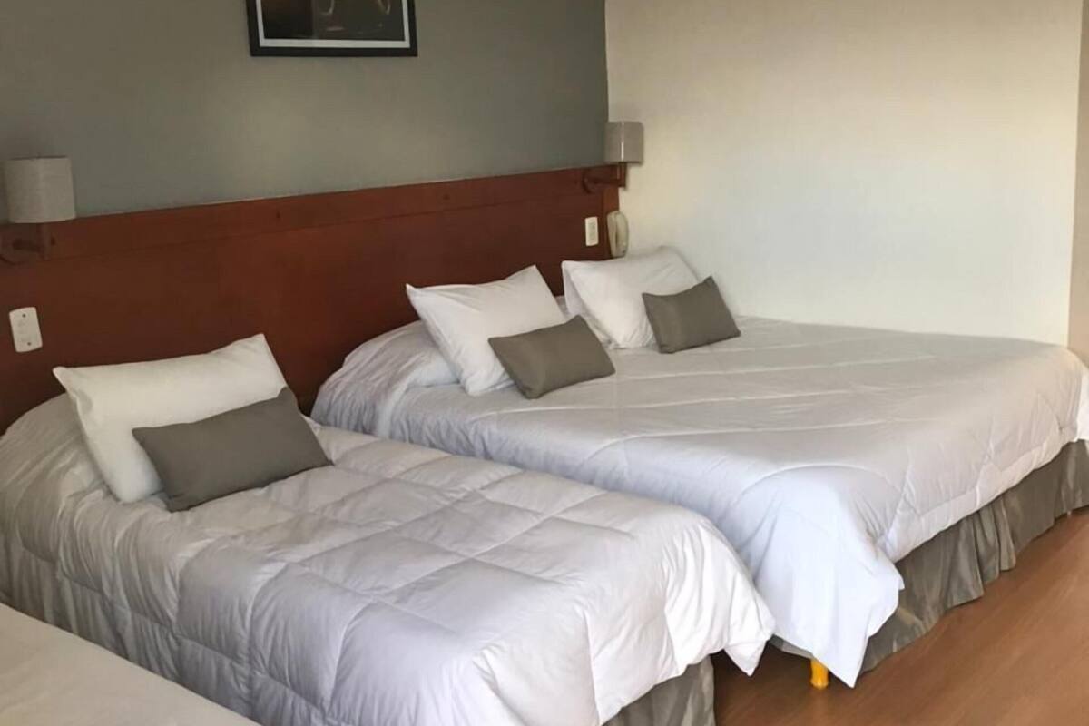 A hotel room with two beds, a ceiling fan, a framed picture on the wall, and a wooden floor.
