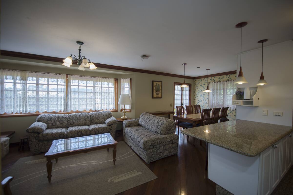 A spacious living room with a sofa, coffee table, and dining area with chairs and a table.