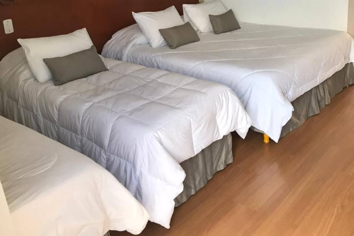 A hotel room with two beds, a ceiling fan, a framed picture on the wall, and a wooden floor.