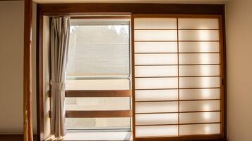 A traditional Japanese room with tatami flooring, a shoji screen, and a sliding door.