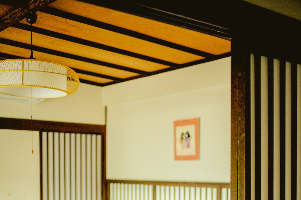 Une pièce de style japonais traditionnel, avec des tatamis, un plafond bas en bois et une lanterne en papier suspendue.