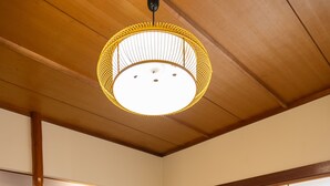 Una habitación japonesa tradicional con suelo de tatami, una mesa de madera, un televisor y un panel corredero shoji.
